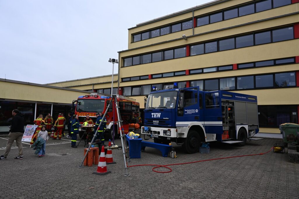 Feuerwehrfahrzeuge und Einsatzkräfte vor einem Schulgebäude.