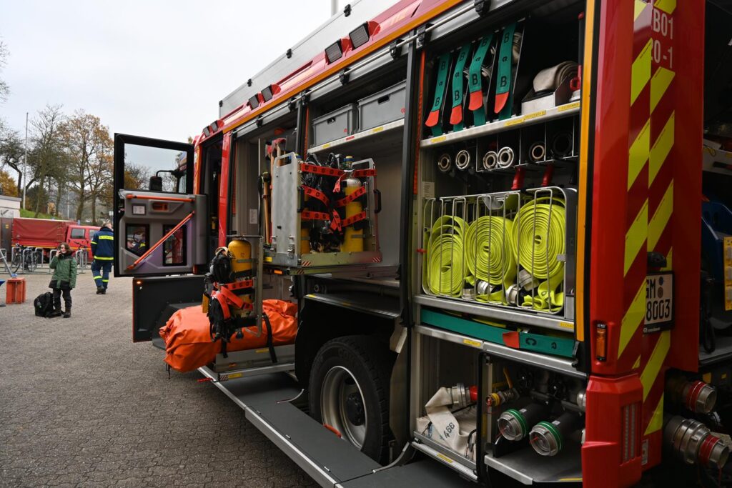 Feuerwehrfahrzeug mit offenen Aufbewahrungsfächern und Ausrüstung sichtbar.
