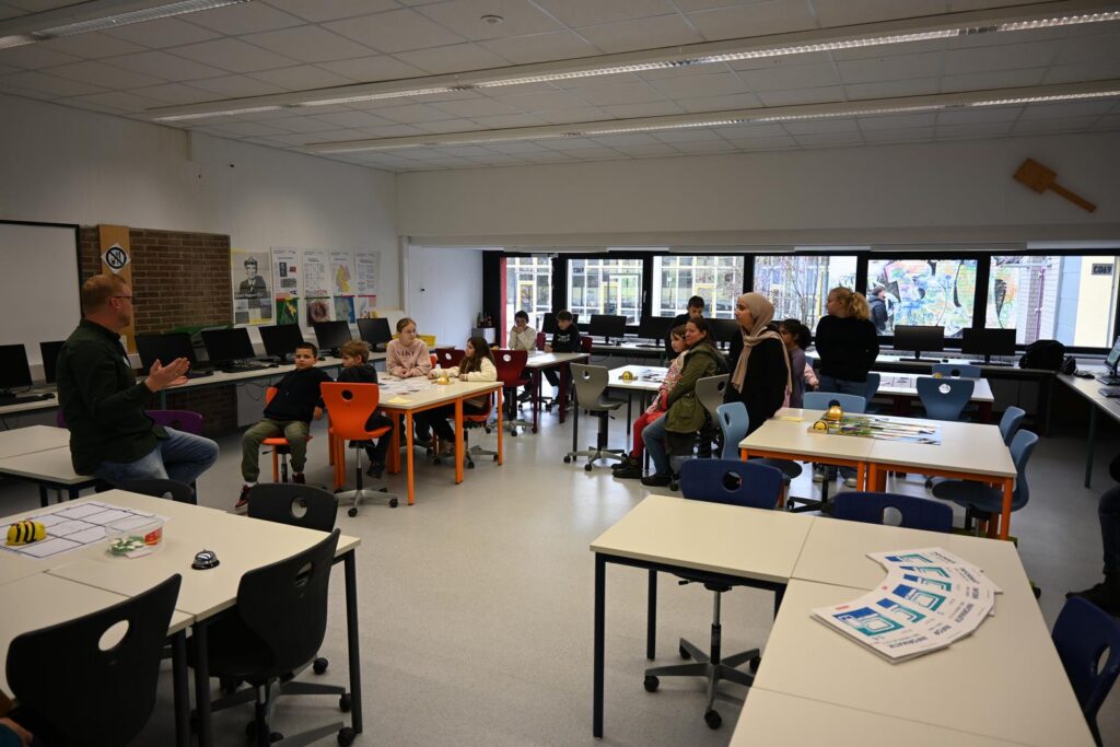 Eine Gruppe von Personen sitzt und steht in einem Klassenraum mit Computern.