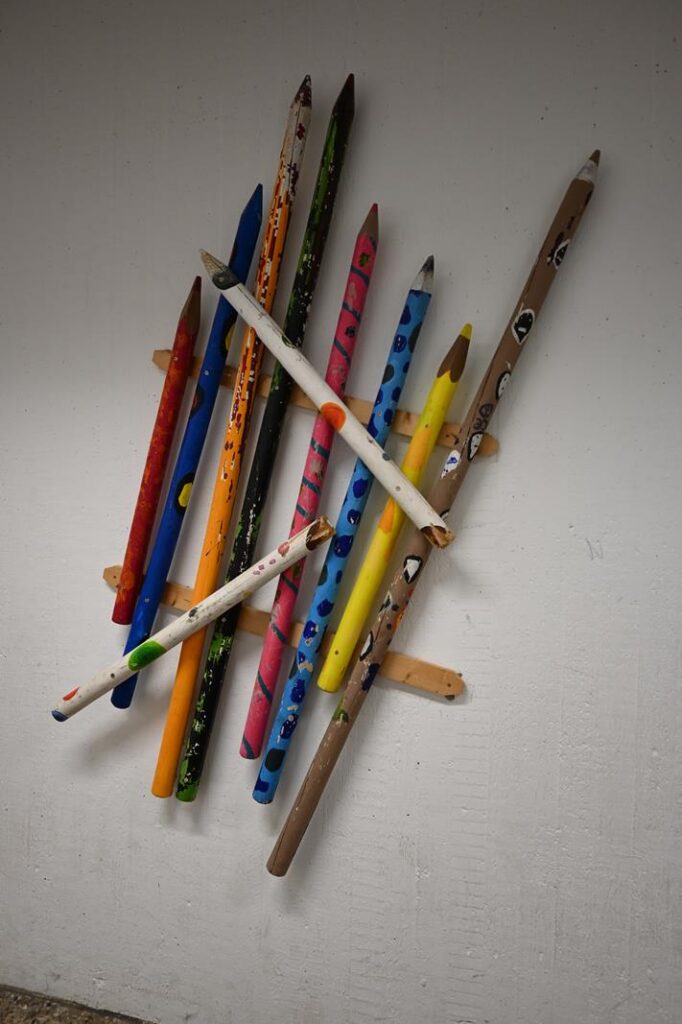 Bunt bemalte Bastelstifte sind an einer Wand befestigt.