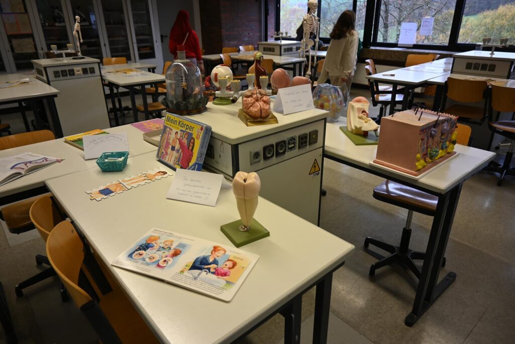Tische im Klassenraum mit verschiedenen Schülerprojekten und Materialien.