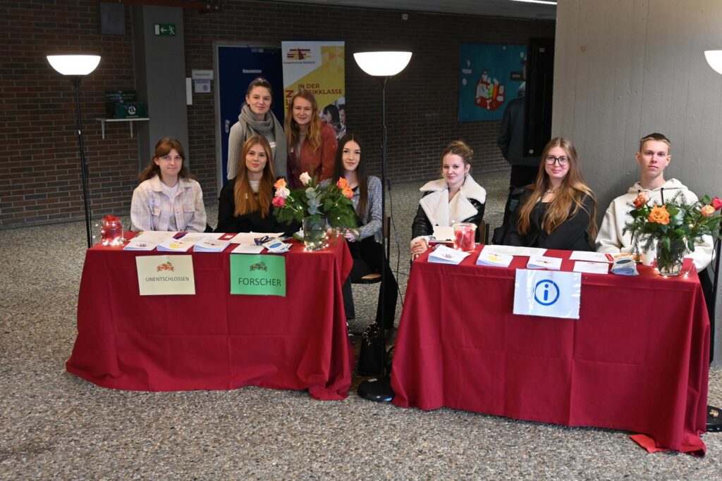 Schülerinnen und Schüler an Informationsständen mit Blumen und Broschüren.