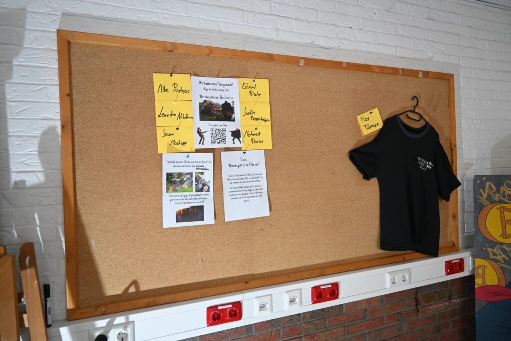 Pinnwand mit Informationen und einem T-Shirt daneben.