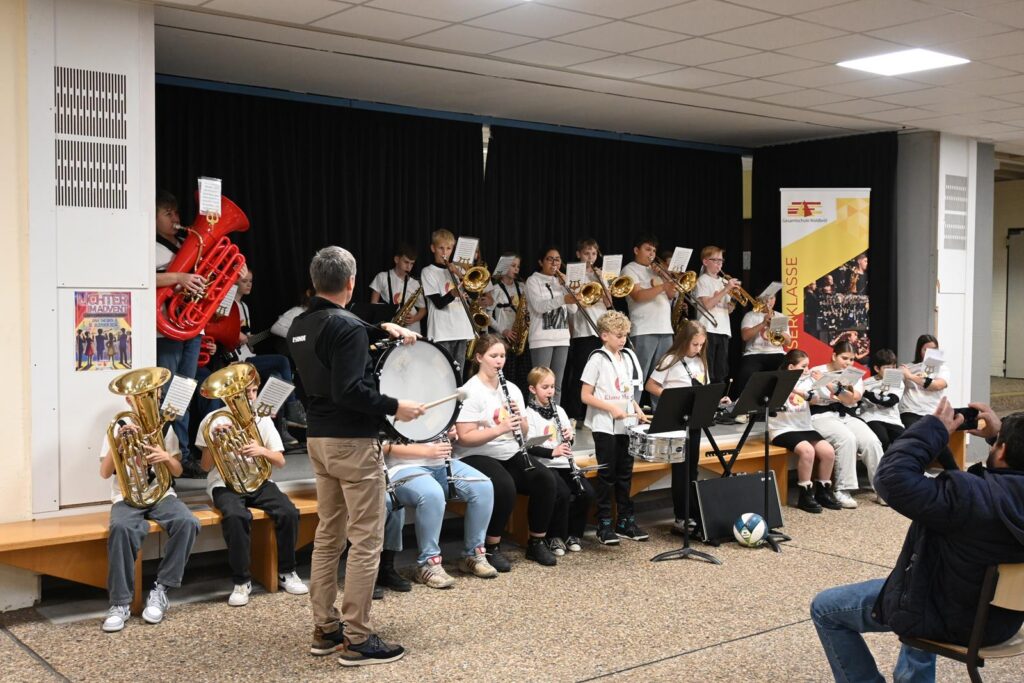 Blaskapelle mit Schülern bei einem Auftritt in der Aula.