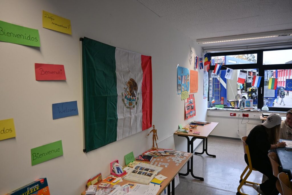 Mexikanische Flagge an der Wand, Tische mit Informationsmaterialien im Klassenraum.