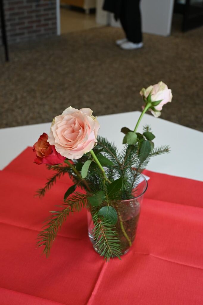 Rosen in einer Vase auf einem roten Tisch.