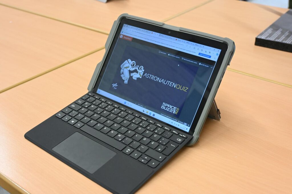 Tablet mit Tastatur auf einem Tisch, Bildschirm zeigt eine Website.