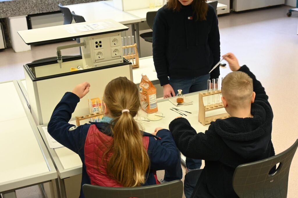 Schüler führen Experimente am Tisch unter Anleitung durch.