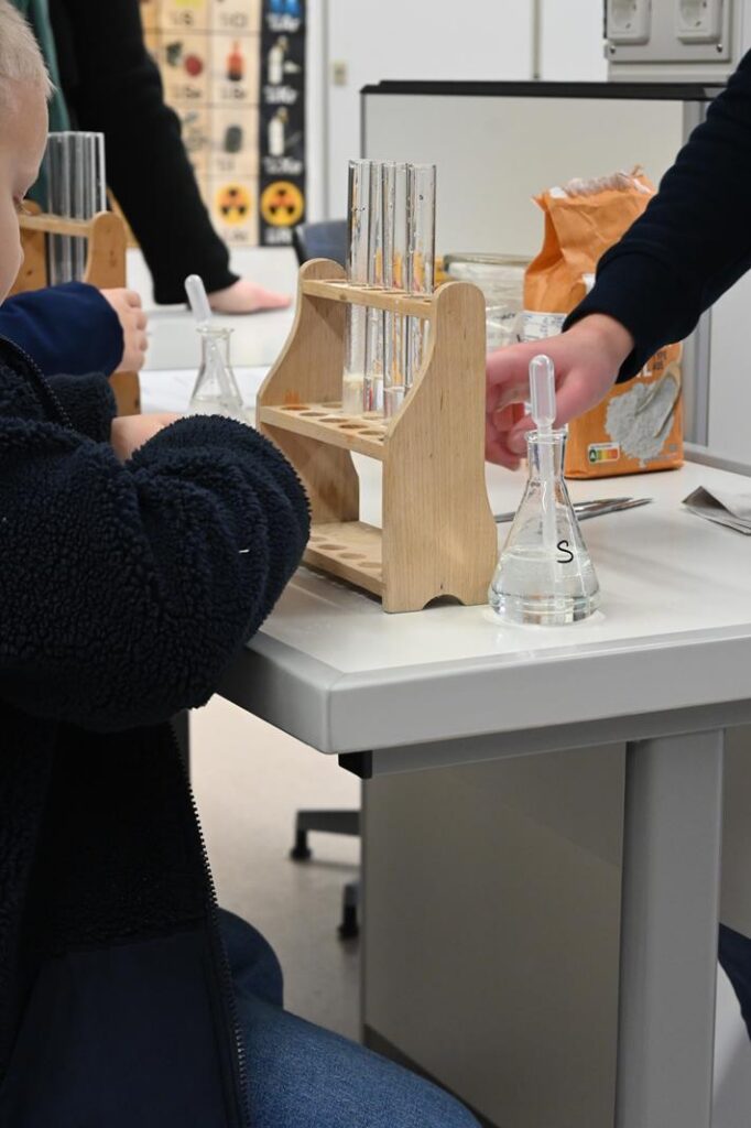 Schüler führen Experimente mit Reagenzgläsern und Flaschen durch.