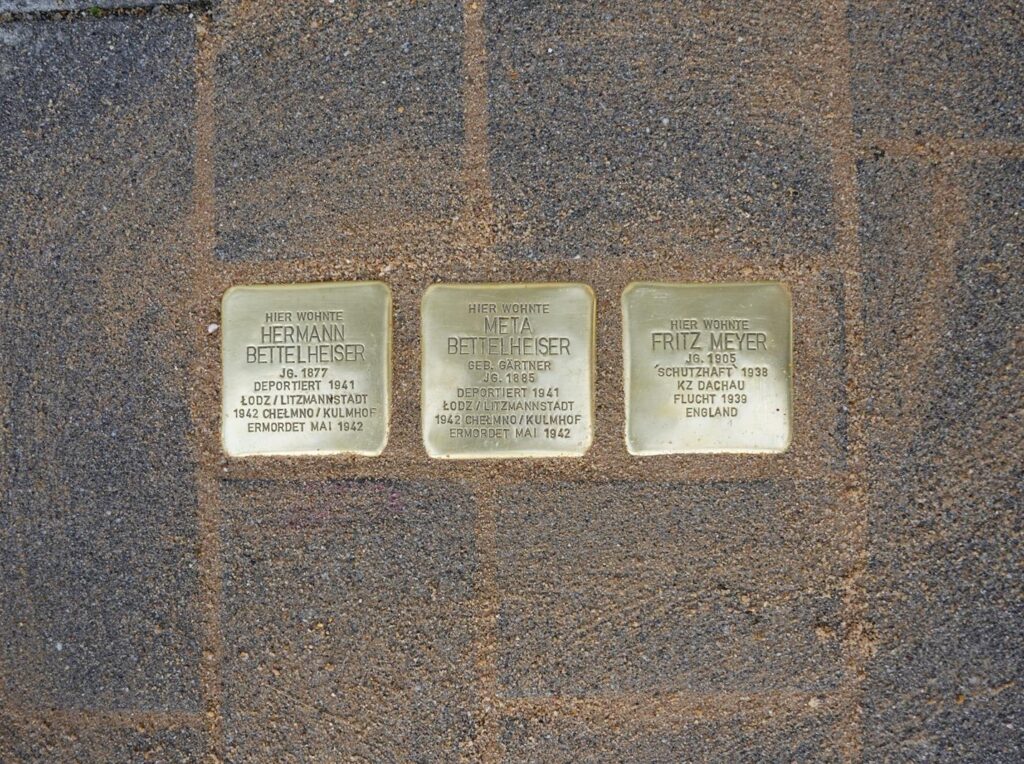 Drei Stolpersteine mit Inschriften in einem Gehweg.
