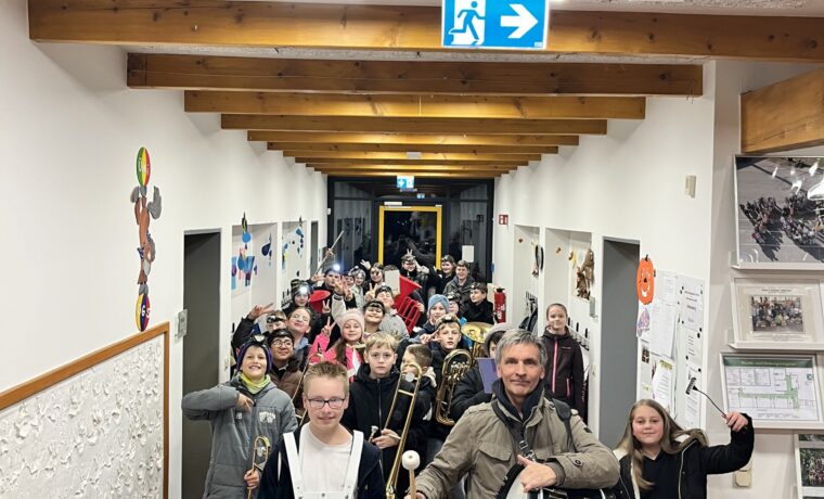 Schüler und Lehrer ziehen mit Instrumenten durch einen Flur.
