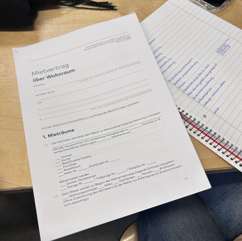 Mietvertrag über Wohnung auf einem Tisch mit Notizen und Schreibmaterial.