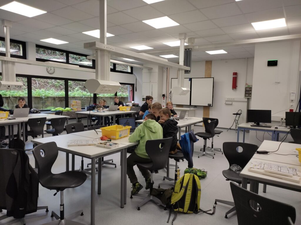 Schüler arbeiten in einem modernen Klassenraum mit Tischen und Stühlen.