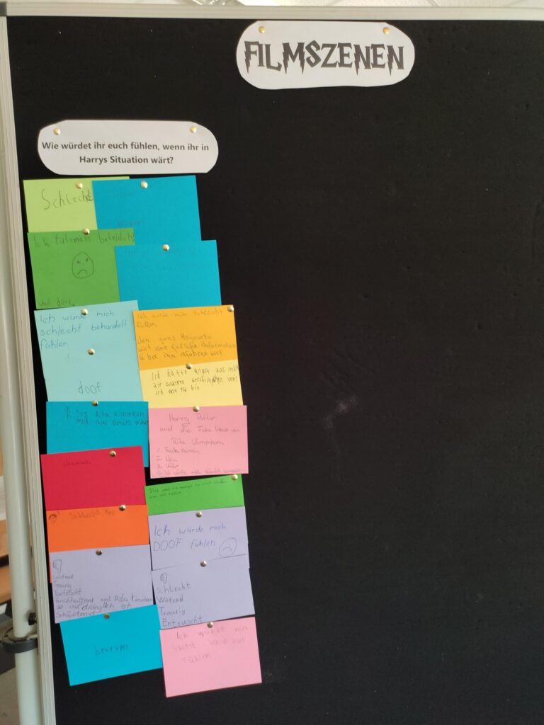 Bunte Notizzettel mit Film-Szenen an einer schwarzen Wandtafel.