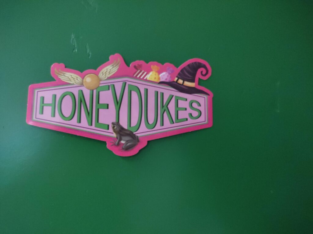 Buntes Schild mit dem Schriftzug "HONEYDUKES" auf grünem Hintergrund.