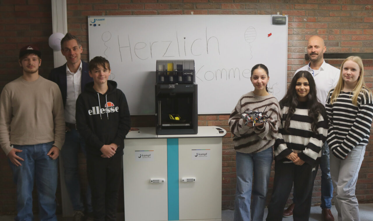 Gruppe von Schülern und Lehrern vor einem Spendenautomaten in einem Klassenraum.
