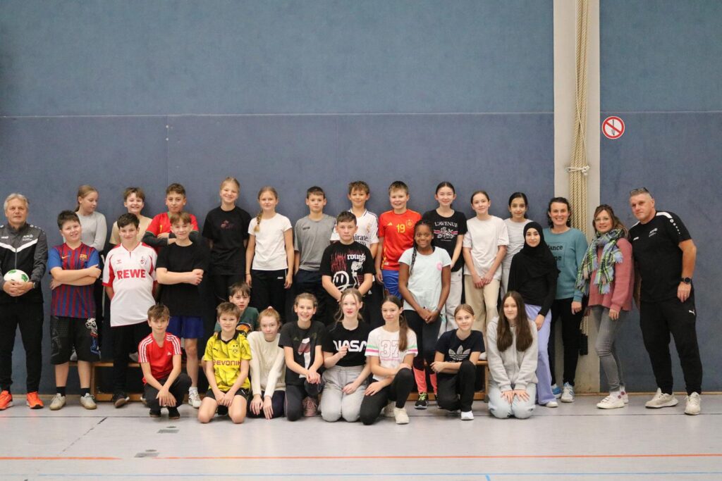 Gruppenfoto von Schülern und Lehrern in einer Sporthalle.