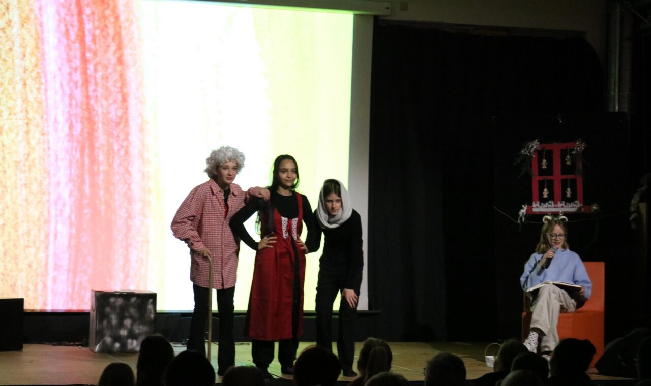 Drei Schauspielerinnen auf der Bühne während einer Theateraufführung.