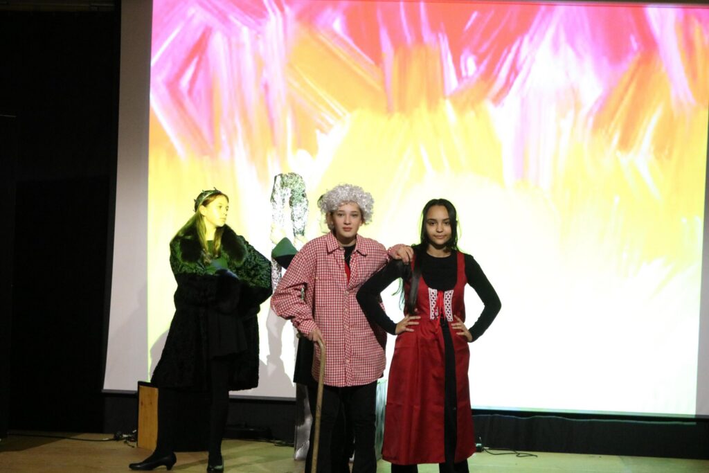 Schüler führen ein Theaterstück mit buntem Hintergrund auf.