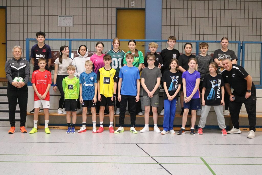Gruppe von Jugendlichen in Sportkleidung, lächelnd in einer Turnhalle.