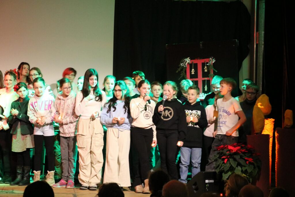 Schülerinnen und Schüler stehen auf der Bühne bei einer Aufführung.