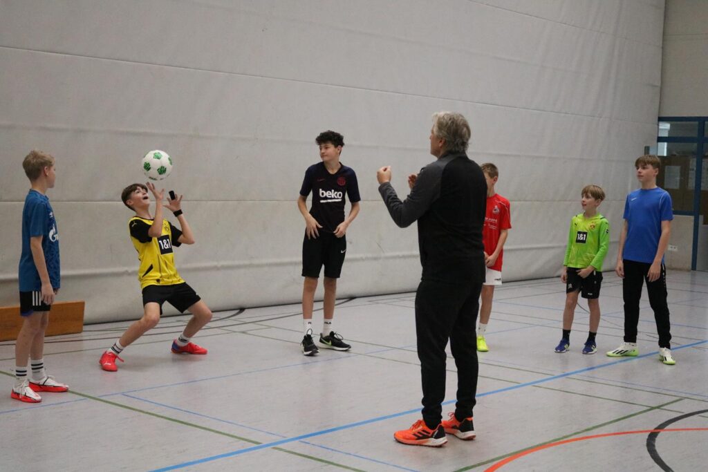Training in einer Sporthalle mit Jugendlichen, die Fußball spielen und trainieren.