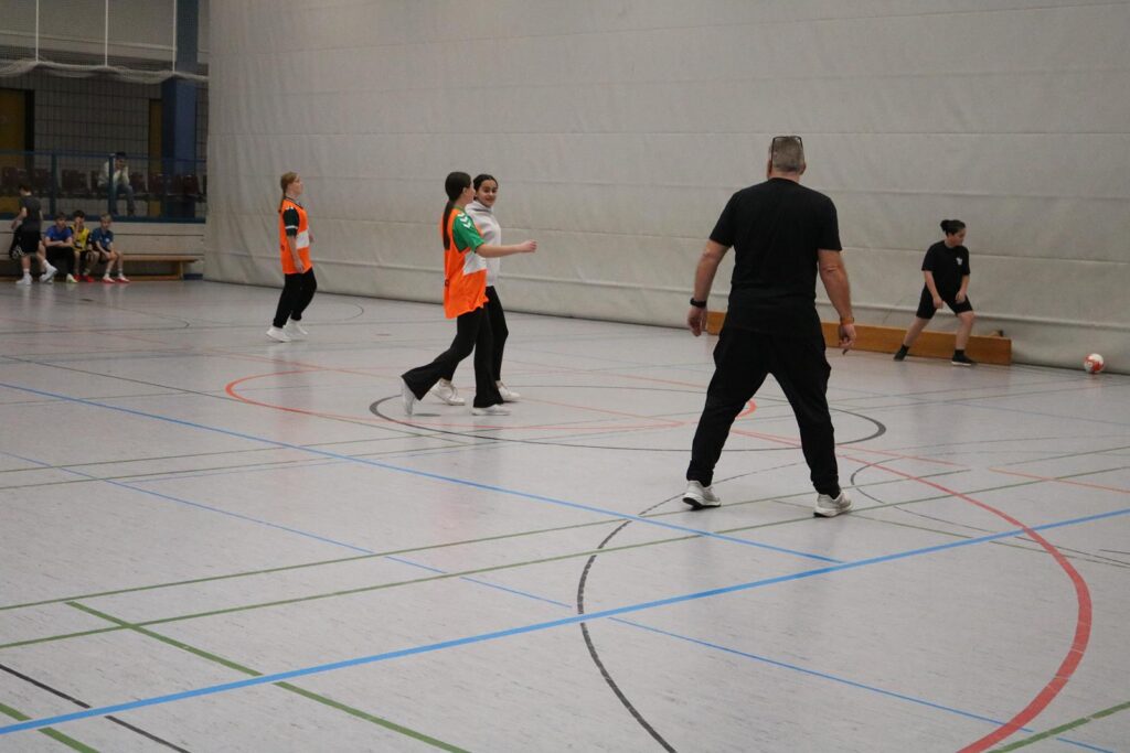 Sportliche Aktivitäten in einer Turnhalle mit Spielern und Trainer.