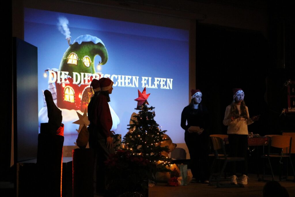 Weihnachtliche Aufführung mit Dekoration und zwei Personen auf der Bühne.