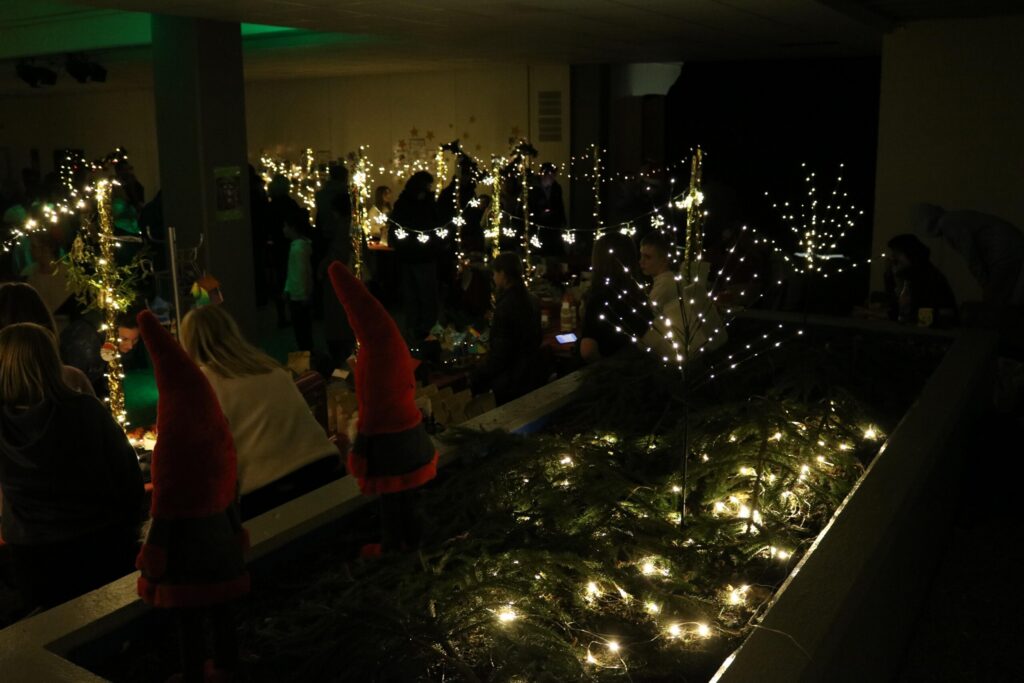 Weihnachtlich dekorierter Raum mit Lichtern und kleinen Weihnachtsbäumen.
