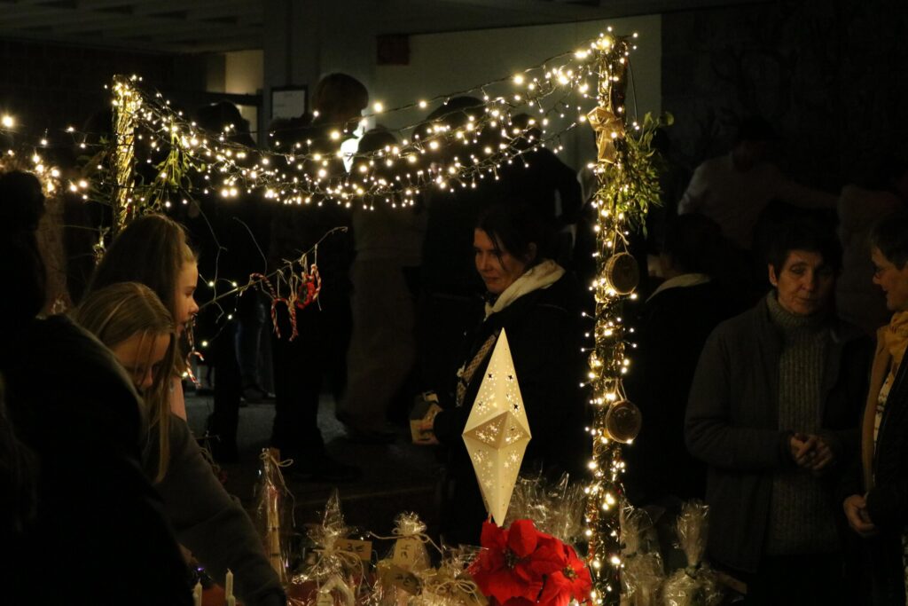 Weihnachtsmarkt mit vielen Lichtern und Besucherinnen, festliche Stimmung.