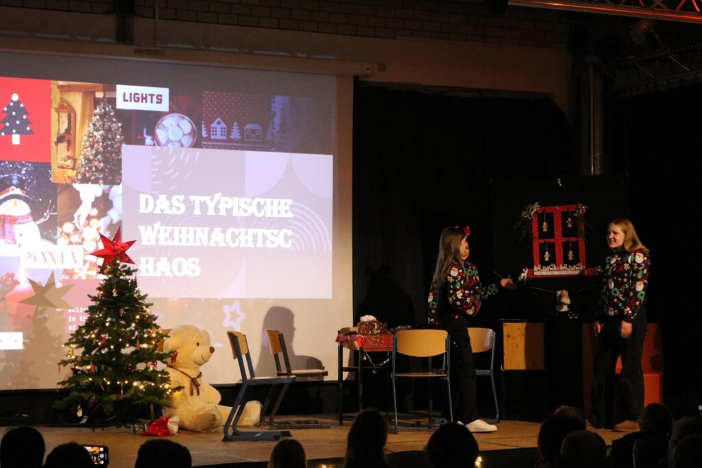 Zwei Personen auf einer Bühne während einer Weihnachtsshow mit Dekoration.