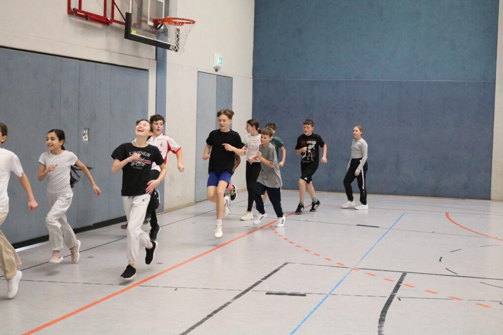 Schüler rennen in einer Turnhalle während des Sportunterrichts.