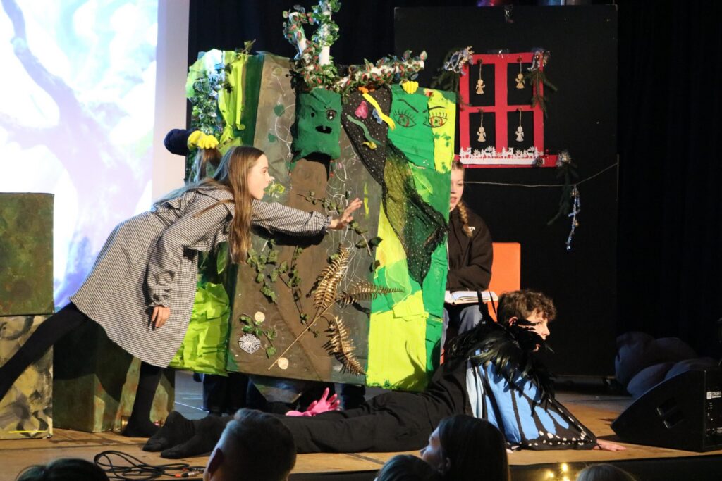 Schüler führen ein Theaterstück mit Kulisse und Kostümen auf.