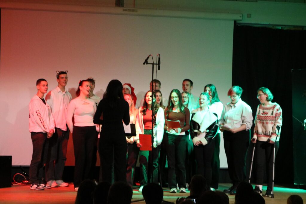 Schüler singen in einem festlichen Auftritt auf einer Bühne.