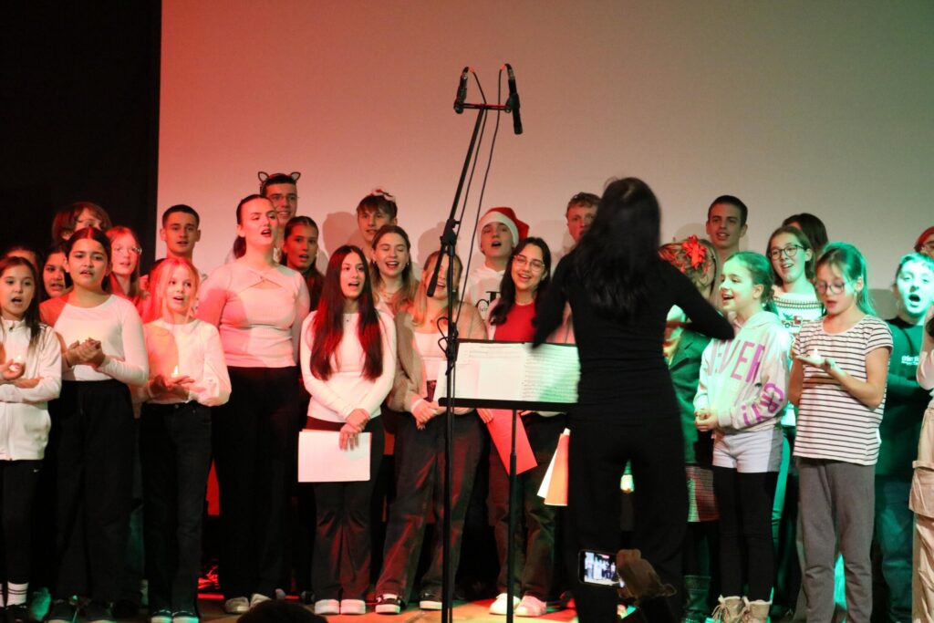 Choraufführung mit Sängerinnen und Sängern, Dirigentin im Vordergrund.