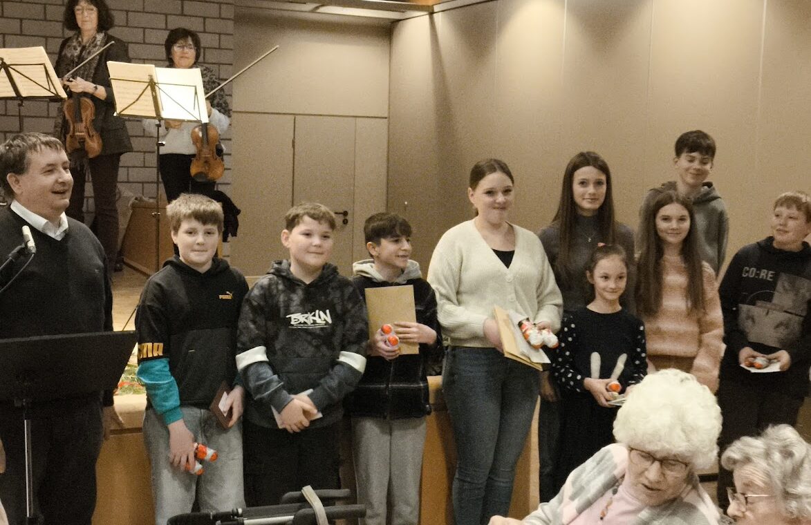 Gruppenbild von Schülern mit einem Lehrer und Musikern im Hintergrund.