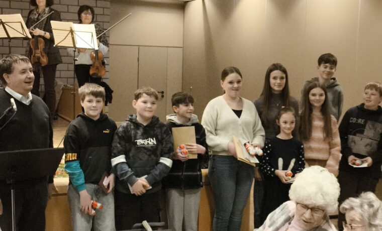 Gruppenbild von Schülern mit einem Lehrer und Musikern im Hintergrund.