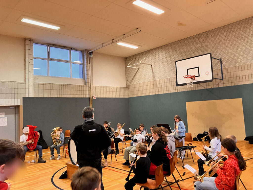 SchülerInnen proben in einem Klassenzimmer mit verschiedenen Musikinstrumenten.