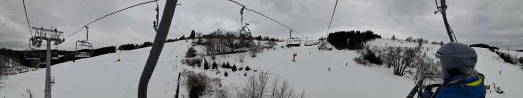 Blick auf eine schneebedeckte Landschaft von einem Skilift aus.