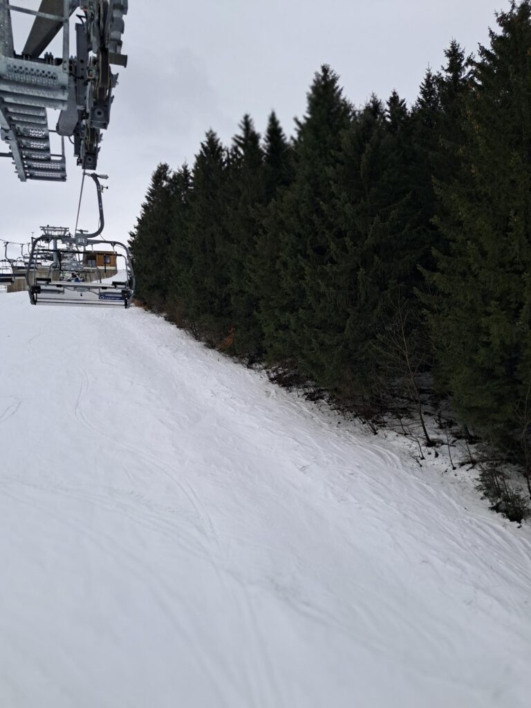 Skilift in verschneiter Landschaft mit Tannenbäumen.