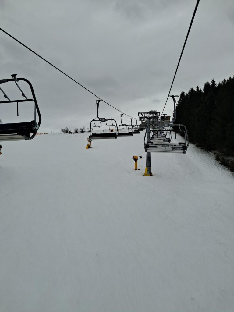 Skilift mit weißen Pisten unter einem grauen Himmel.