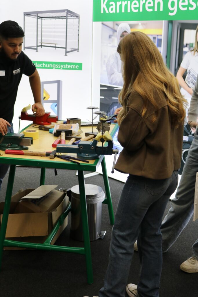 Schülerinnen und Schüler arbeiten an einem Tisch mit Werkzeugen und Materialien.