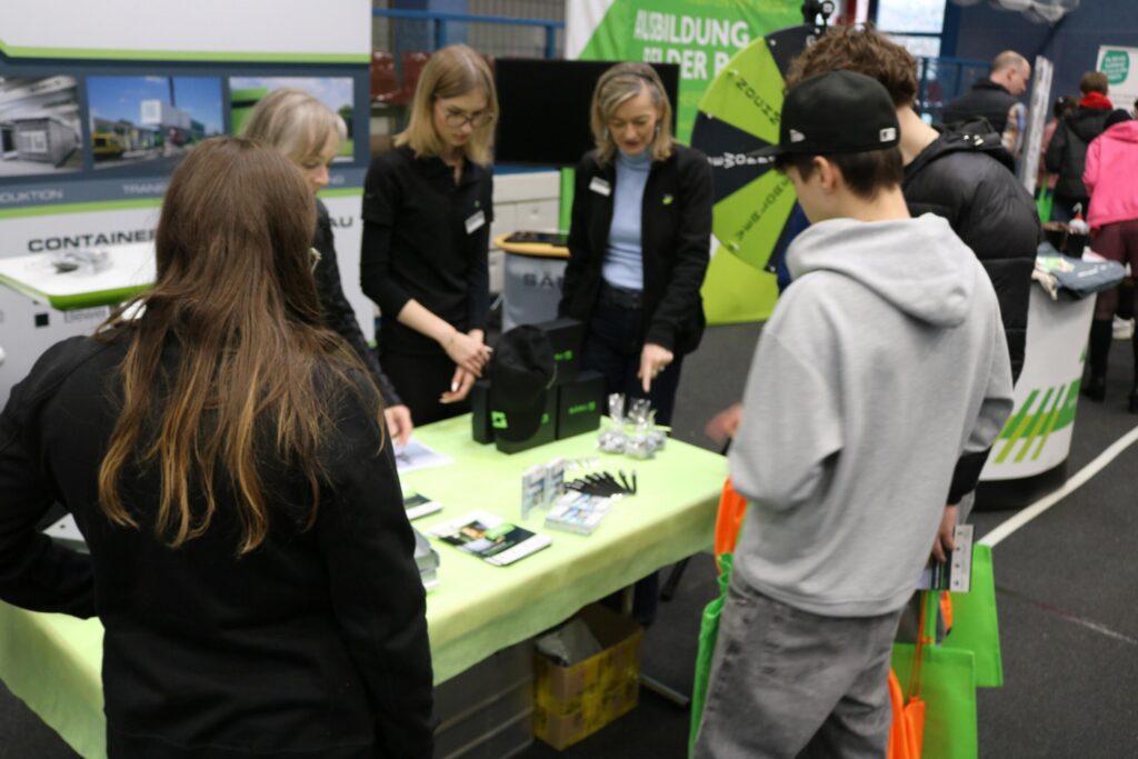 Messebesucher am Stand, Beratung durch Fachkräfte, Informationsmaterialien ausgelegt.