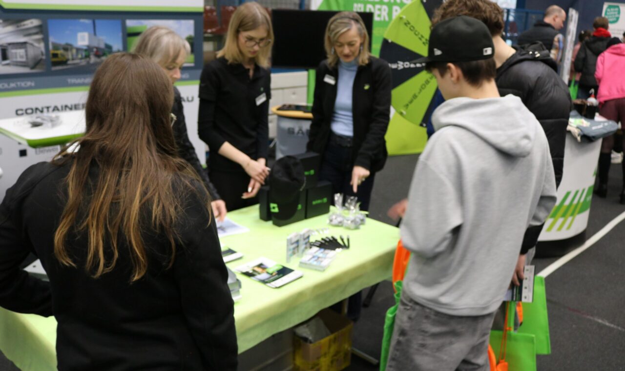 Messebesucher am Stand, Beratung durch Fachkräfte, Informationsmaterialien ausgelegt.