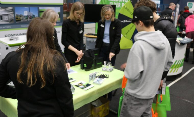 Messebesucher am Stand, Beratung durch Fachkräfte, Informationsmaterialien ausgelegt.