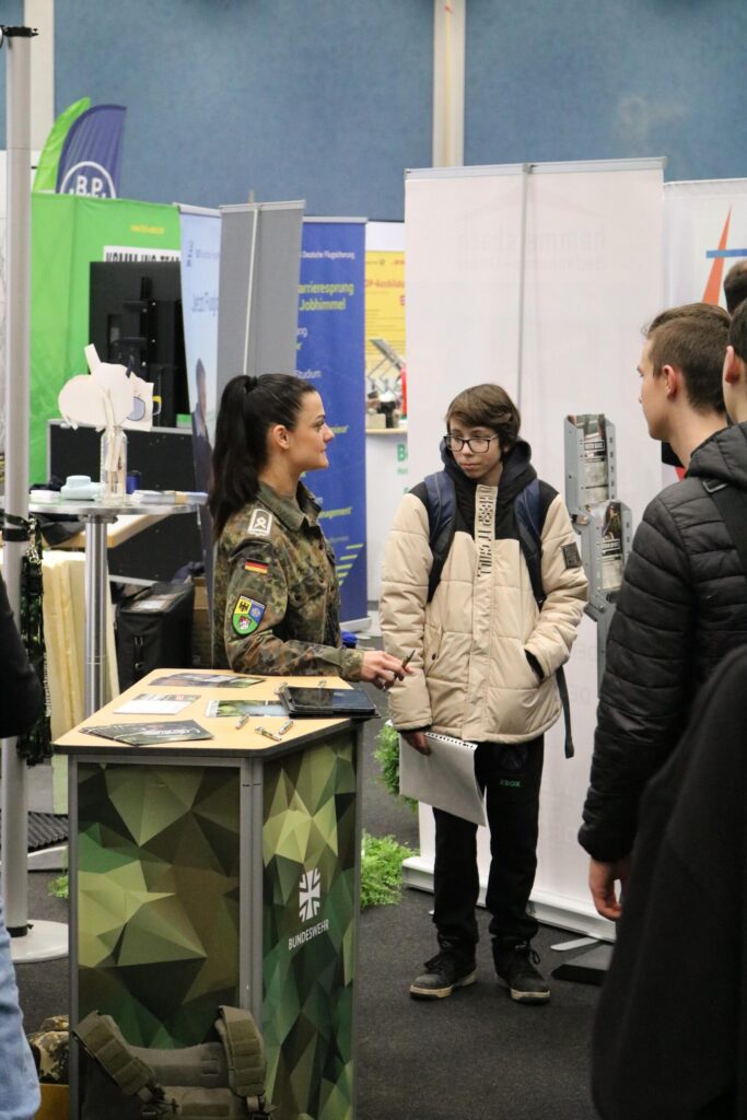 Junge Erwachsene am Stand der Bundeswehr auf einer Messe.