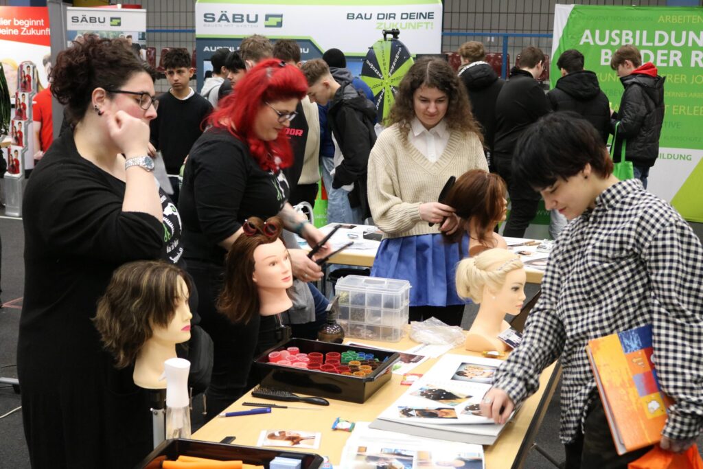 Messe mit Ausstellern, die Friseurprodukte und Modelle präsentieren.