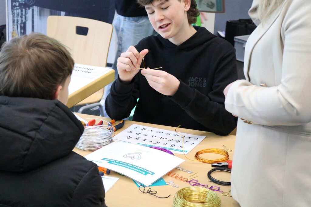 Schüler erklärt eine Aktivität am Tisch mit Bastelmaterialien.