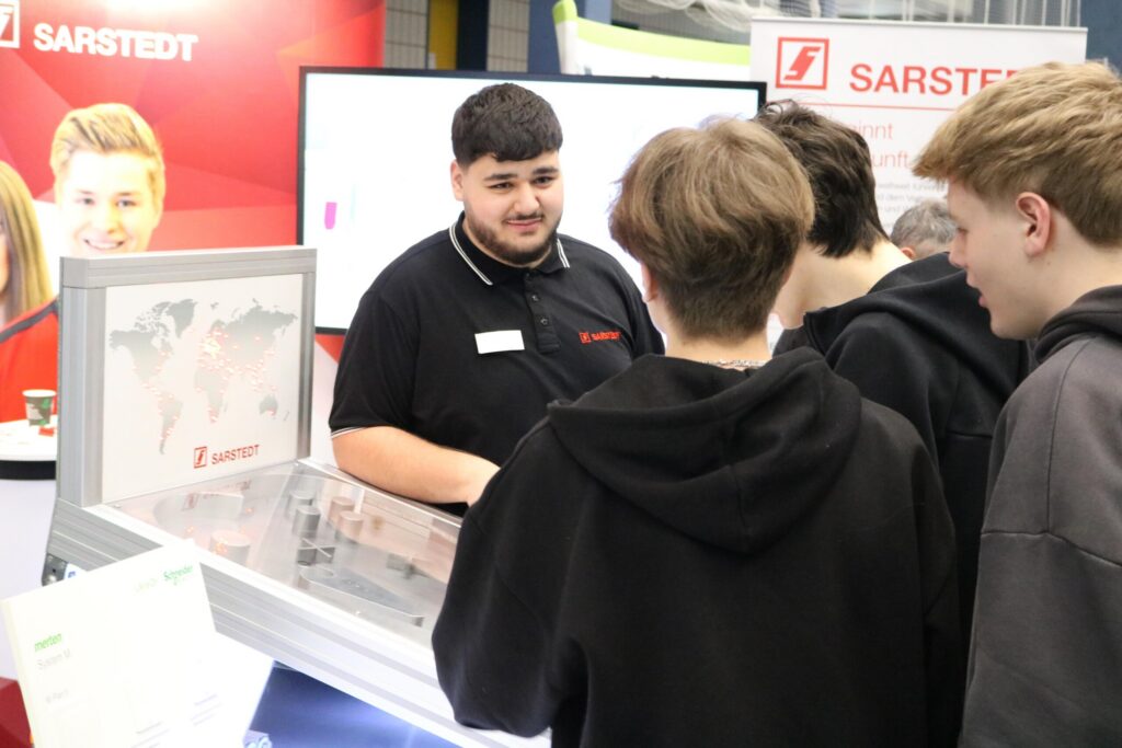 Ein Stand mit Präsentatoren und Besuchern bei einer Messe.