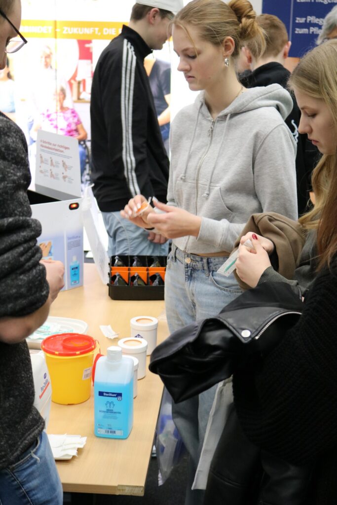 Studierende an einem Stand, mit Materialien zum Experimentieren.